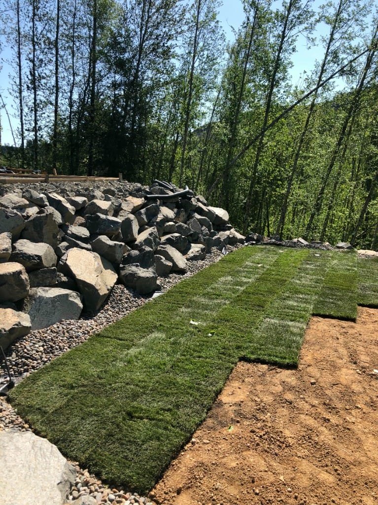 Boulder retaining wall with drainage system and landscaping - Bloomstrom Construction