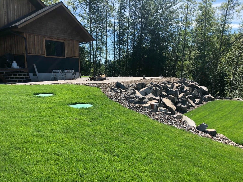 Completed rock retaining wall with lawn and patio - Bloomstrom Construction finished project