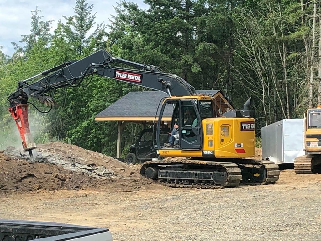 John Deere excavator with hydraulic hammer breaking rocks - Bloomstrom Construction heavy equipment